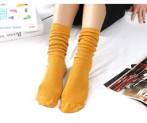 Detail of yellow ribbed knit slouch socks worn by a model in a cozy home setting