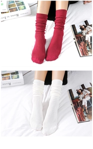 Close-up of red and white cotton slouch socks with thick knitted texture on a white bed