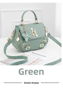 Close-up of green leather handbag featuring pearl H hardware and daisy embroidery details