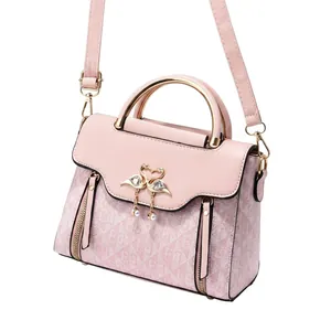 Dettaglio borsa rosa con decorazione a cigno dorato e raffinati pendenti di perle