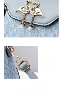 Dettaglio dell'accessorio cigno dorato con perle su borsa azzurra a motivi geometrici