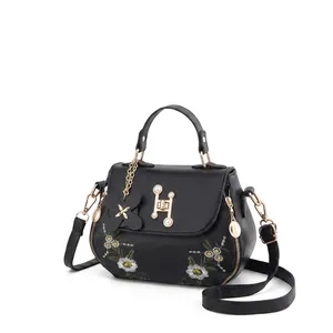 Detailed close-up of matte leather shoulder bag with daisy embroidery and pearl H-clasp