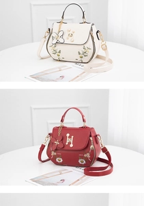 Detail view of floral embroidery and pearl-accented H-buckle on stylish leather handbags