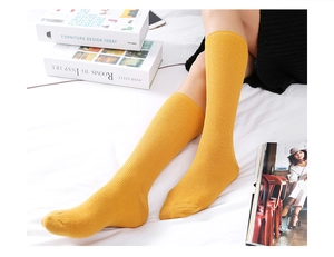 Close-up of ginger yellow slouch socks with vertical ribbed knit texture on white fabric