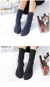 Detail of navy and black ribbed knit slouch socks showing premium texture on a bed