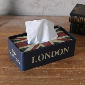 Close-up of vintage Union Jack metal tissue box on a rustic wooden table with retro books