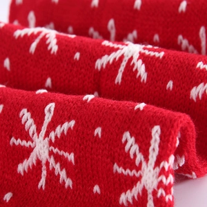 Macro shot of thick red knitted scarf with white snowflake patterns and soft texture