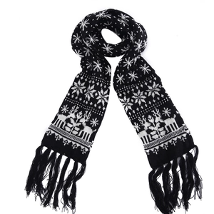 Detailed close-up of a black knit scarf with white reindeer and snowflake patterns and tassels