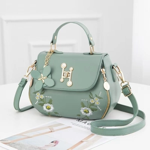 Green leather handbag with daisy embroidery and pearl lock shown at a 45-degree angle