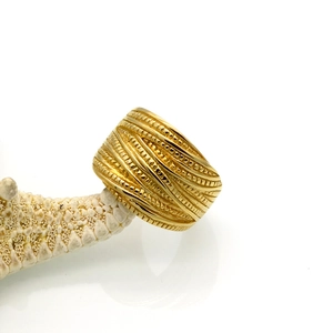 Close-up of golden wide braided steel ring with intricate bead textures and woven layers