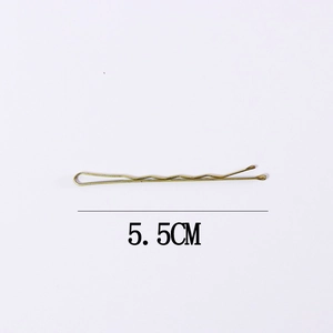 Detail view of 5.5cm golden metal hair clip featuring minimalist cross design on white back