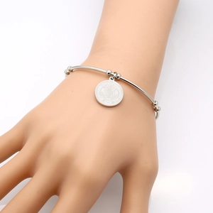 Detailed view of silver Saint Benedict religious medal charm on a sleek bangle bracelet
