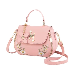 Pink faux leather handbag with daisy embroidery and pearl H clasp shown on white background
