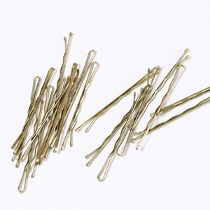 Detailed view of wavy metallic hairpins in gold and bronze finish on white surface