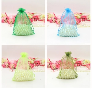 Detail of organza drawstring bags in four green shades with white faux pearl filling