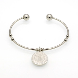 Detail of silver St. Benedict medal charm on a stainless steel open bangle bracelet
