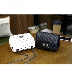 Quilted mini square bags with silver studs and chain straps on a wooden table