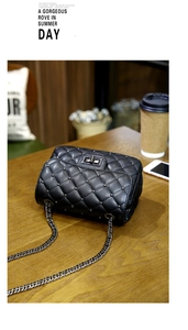 Detail of black quilted chain bag with silver studs on a wooden cafe table surface