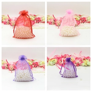 Detail view of colorful organza drawstring bags with pearls in red, pink and purple