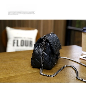 Detail of black quilted leather shoulder bag with silver studs and chain strap