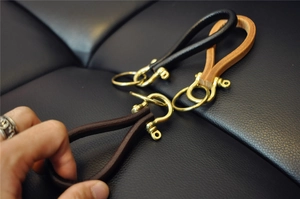 Detailed view of handmade brass horseshoe keychains in black, dark brown, and light brown