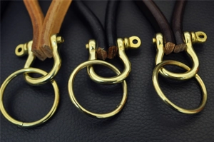 Detailed view of handmade leather keychains in three colors with brass horseshoe shackles