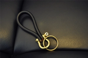 Close-up of black cowhide leather keychain with brass horseshoe buckle and twin metal rings