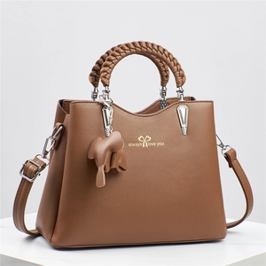 Brown litchi texture handbag with woven handle and elephant charm in a 45-degree view