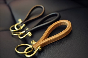 Three premium handmade leather keychains in brown, black and natural tan with brass hardware