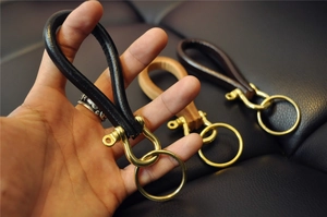 Close-up of handmade brass horseshoe buckles with genuine leather keychains in three colors