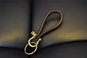 Detail of vintage handmade dark brown leather keychain with solid brass horseshoe buckle
