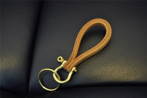 Macro shot of vintage brown cowhide leather keychain with brass horseshoe clasp detail
