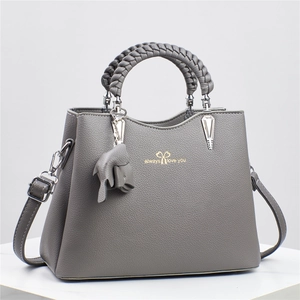 Macro shot of grey lychee leather handbag featuring a woven handle and charm