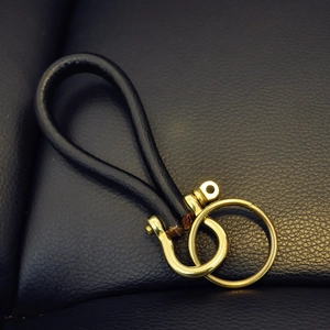 Vintage brass keychain with black leather loop and heavy metal D-ring buckle on leather
