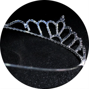 Detailed close-up of a silver crown headband featuring clear rhinestones on a black background