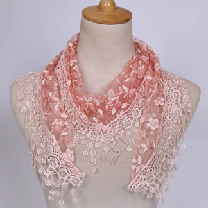 Detail showing pink floral lace embroidery and soft pom-pom fringe on the triangle scarf