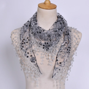 Detail of gray floral lace scarf featuring silver floral appliques and sequin tassel trim