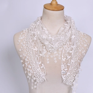 Close-up detail of white floral lace triangle scarf with delicate embroidery and fringed edges