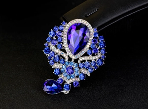 Detail of rhinestone brooch with deep blue pear-cut crystal and silver-toned plating