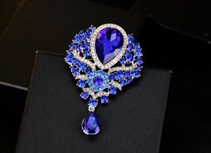 Macro shot of royal blue teardrop crystal brooch with rhinestone details on black box