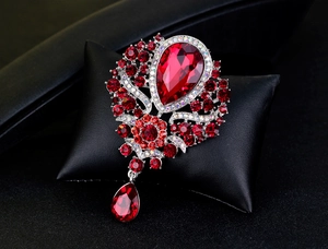 Close-up of red rhinestone flower brooch with teardrop glass pendant on black leather