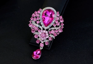 Macro shot of rose pink crystal brooch with teardrop pendant on black display