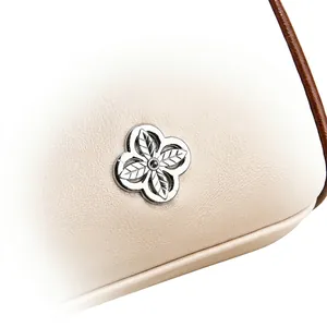 Detail aus beigem Leder mit Litschi-Struktur und silbernem Blumen-Metall-Logo