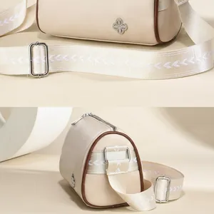 Detailansicht der beigen Boston-Tasche mit silbernem Blumenanhänger und Web-Schultergurt