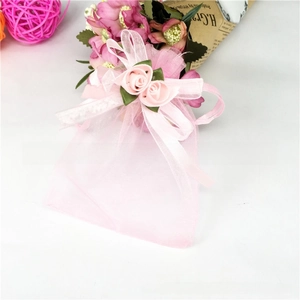 Detail of pink organza drawstring gift bag with elegant ribbon flower and bow accent