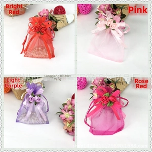 Detail of organza drawstring gift bags in red, pink, purple, and rose with ribbon roses