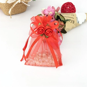 Close-up of red organza gift bag with rose drawstring and white pearl beads inside