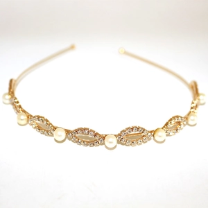 Detailed view of gold headband with round pearls and rhinestone-encrusted leaf accents