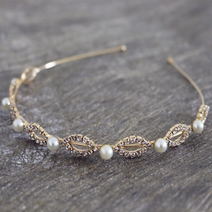 Detailed macro view of golden pearl and rhinestone leaf patterns on bridal headband