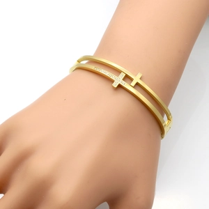 Detail of gold double-layer cross bangle featuring pavé zircon and hollow design